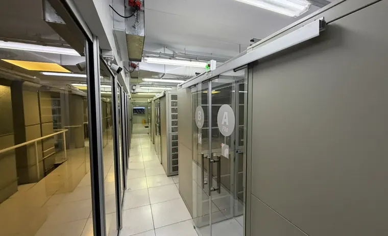 Pasillo de la sala de datos con las jaulas privadas de las filas A y B, señalizadas sobre puertas vidriadas