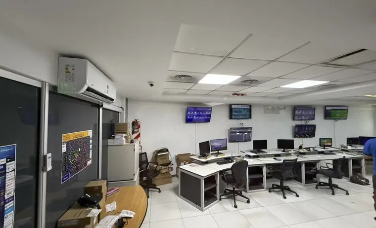 Sala de monitoreo con puestos de operación y cinco pantallas mostrando tableros de estado y métricas de red