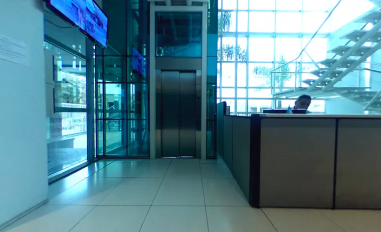 Recepción del datacenter con mostrador atendido, ascensor y fachada vidriada